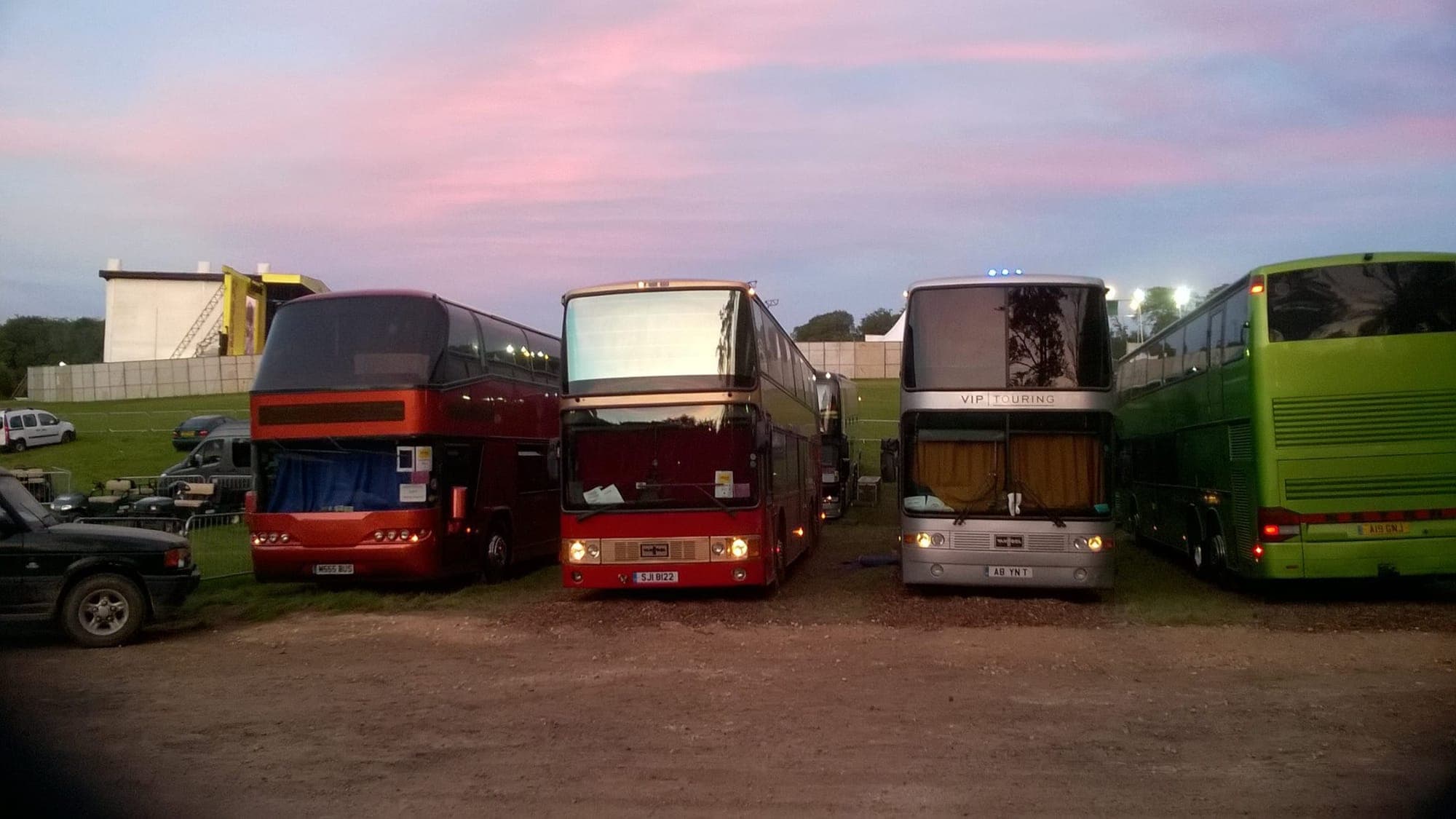 Crew buses parked together at a festival location at dusk