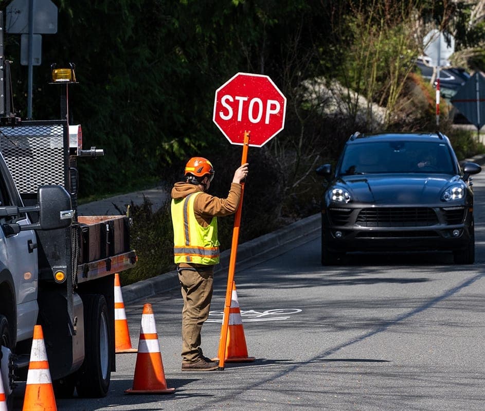 Traffic marshal holding a stop sign beside a controlled road