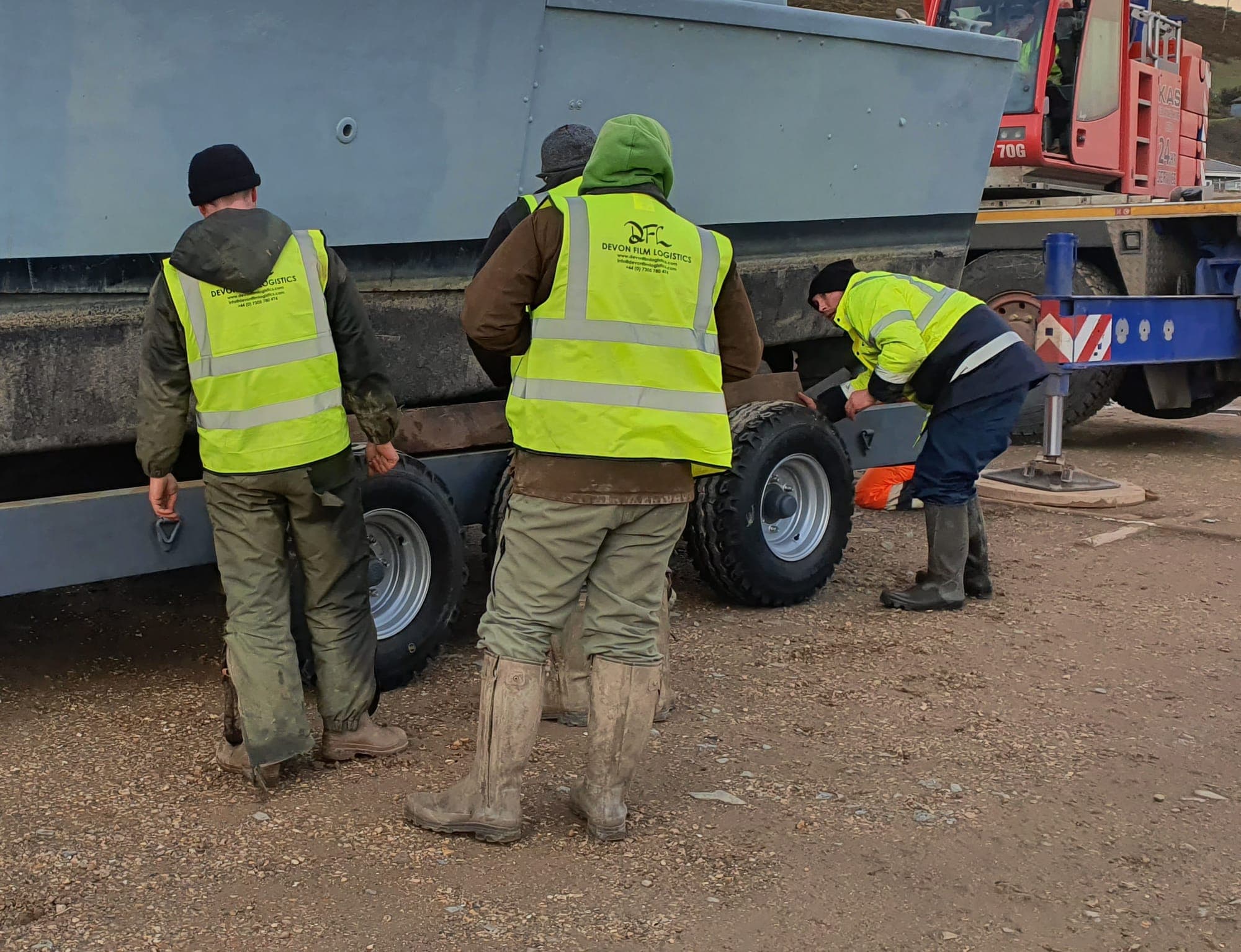 DFL crew securing wheeled equipment beside a transport vehicle