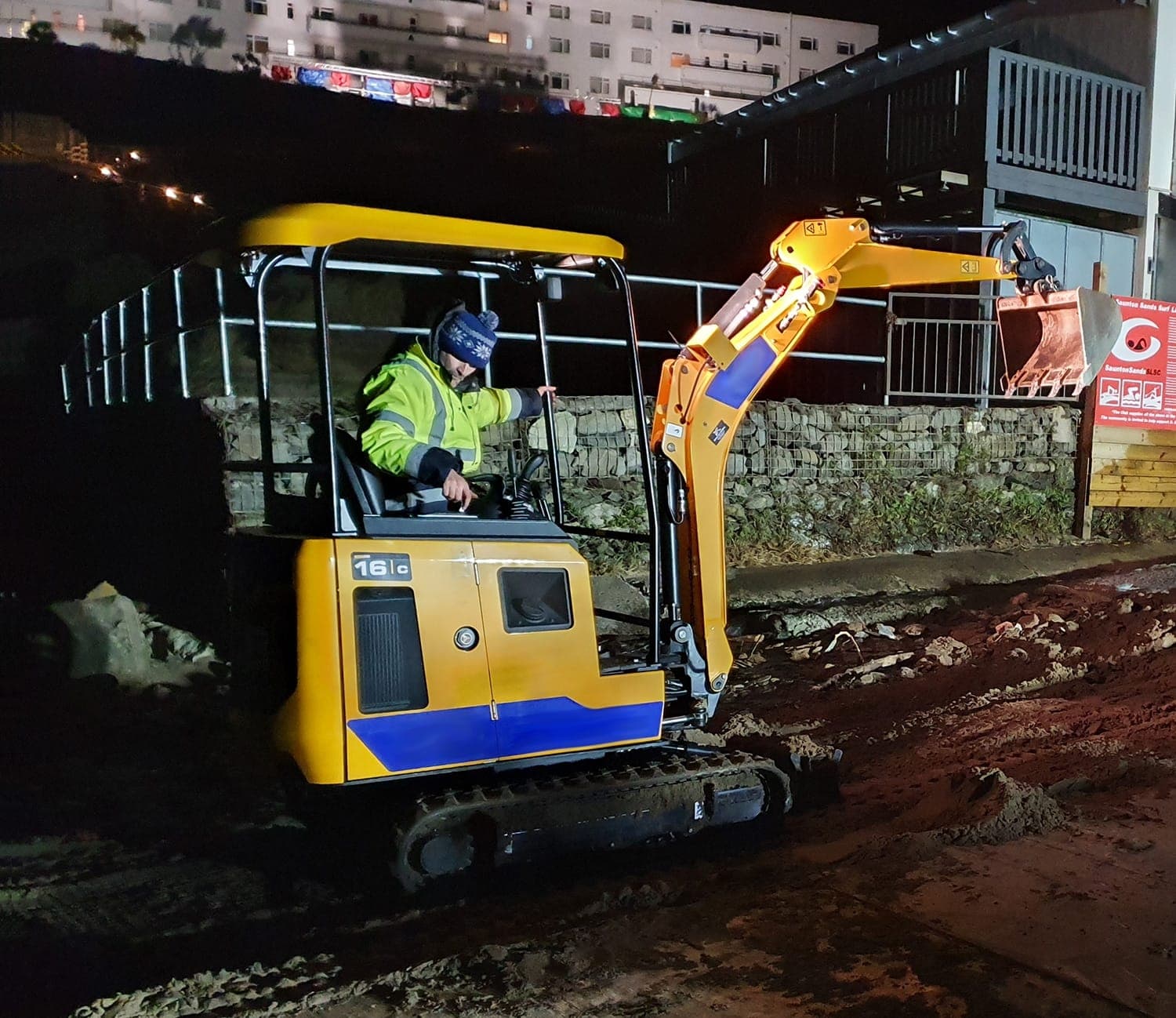 Mini-digger operator working on disturbed ground at night