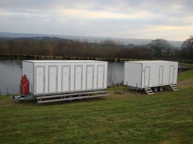 Two mobile shower trailers beside a lake