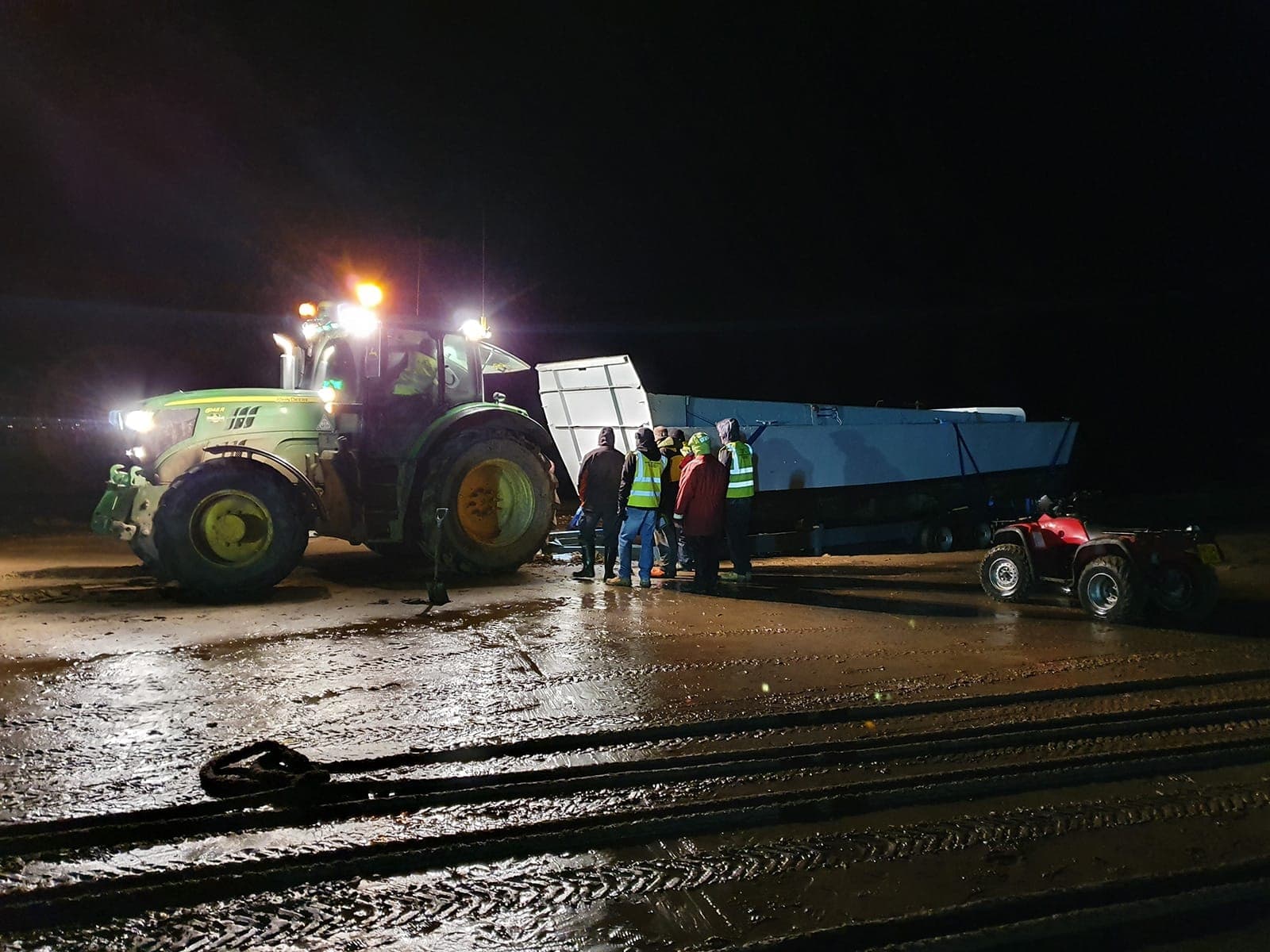 Tractor, work boat and location crew operating on a beach at night