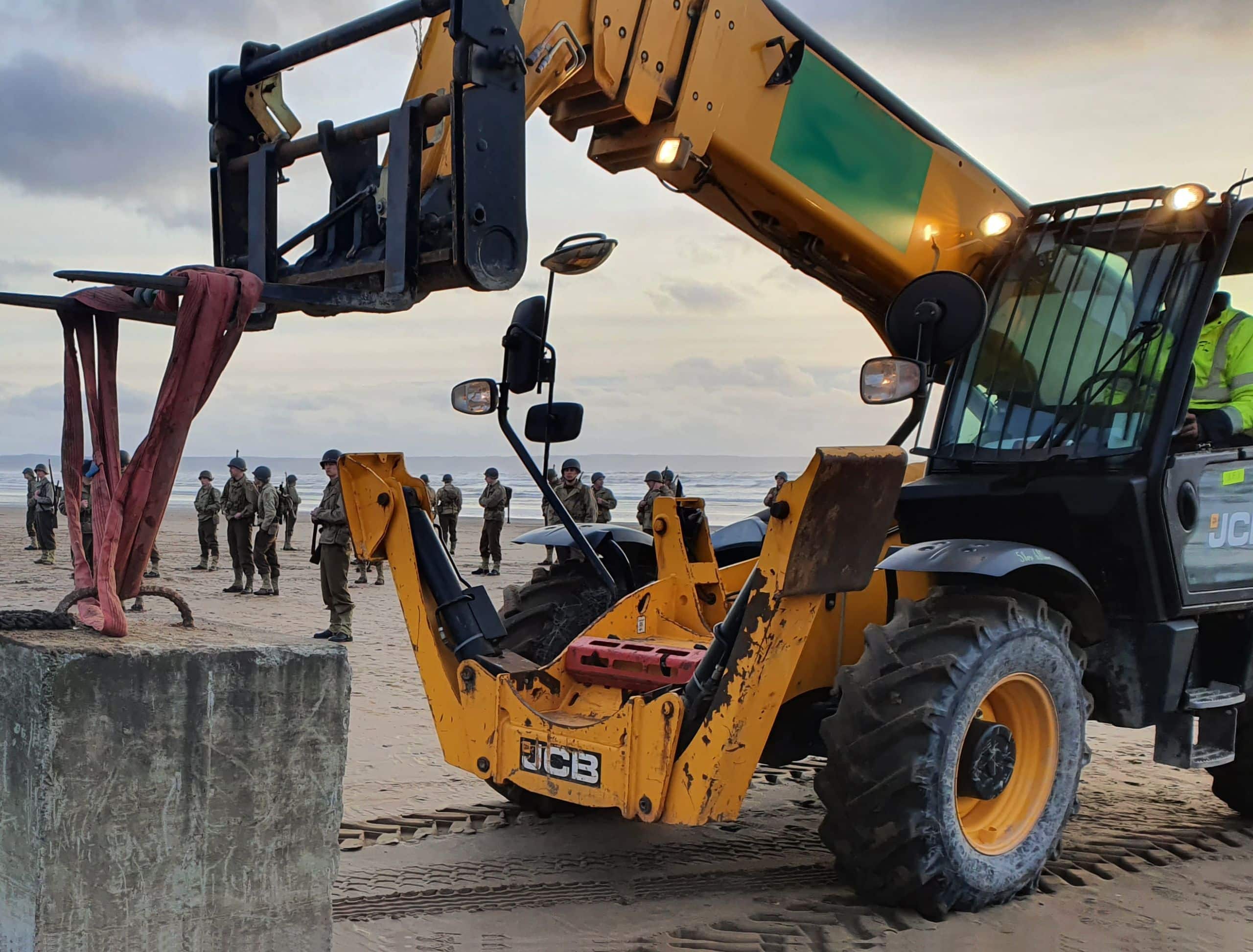 Telehandler working on a beach with costumed performers in the background