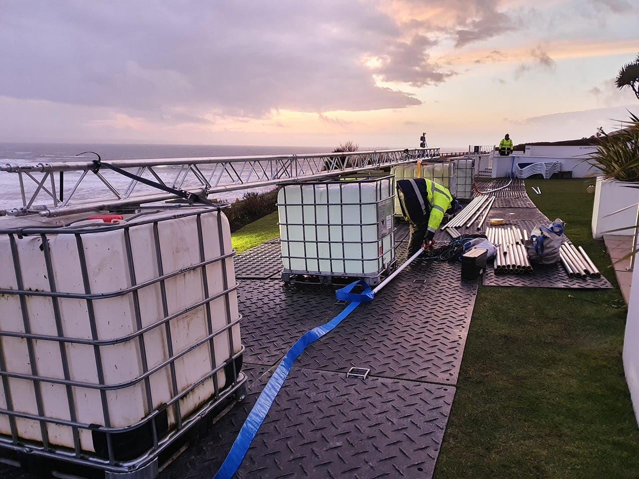 Temporary ground-protection panels installed across grass beside a trailer