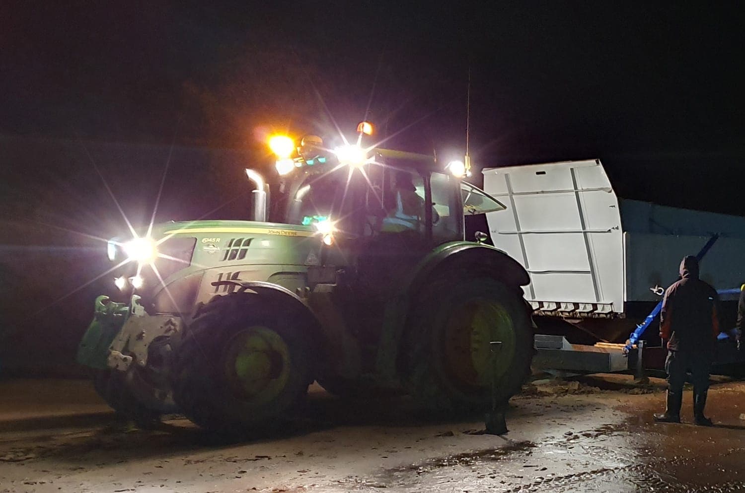 Tractor and crew moving equipment at a location at night