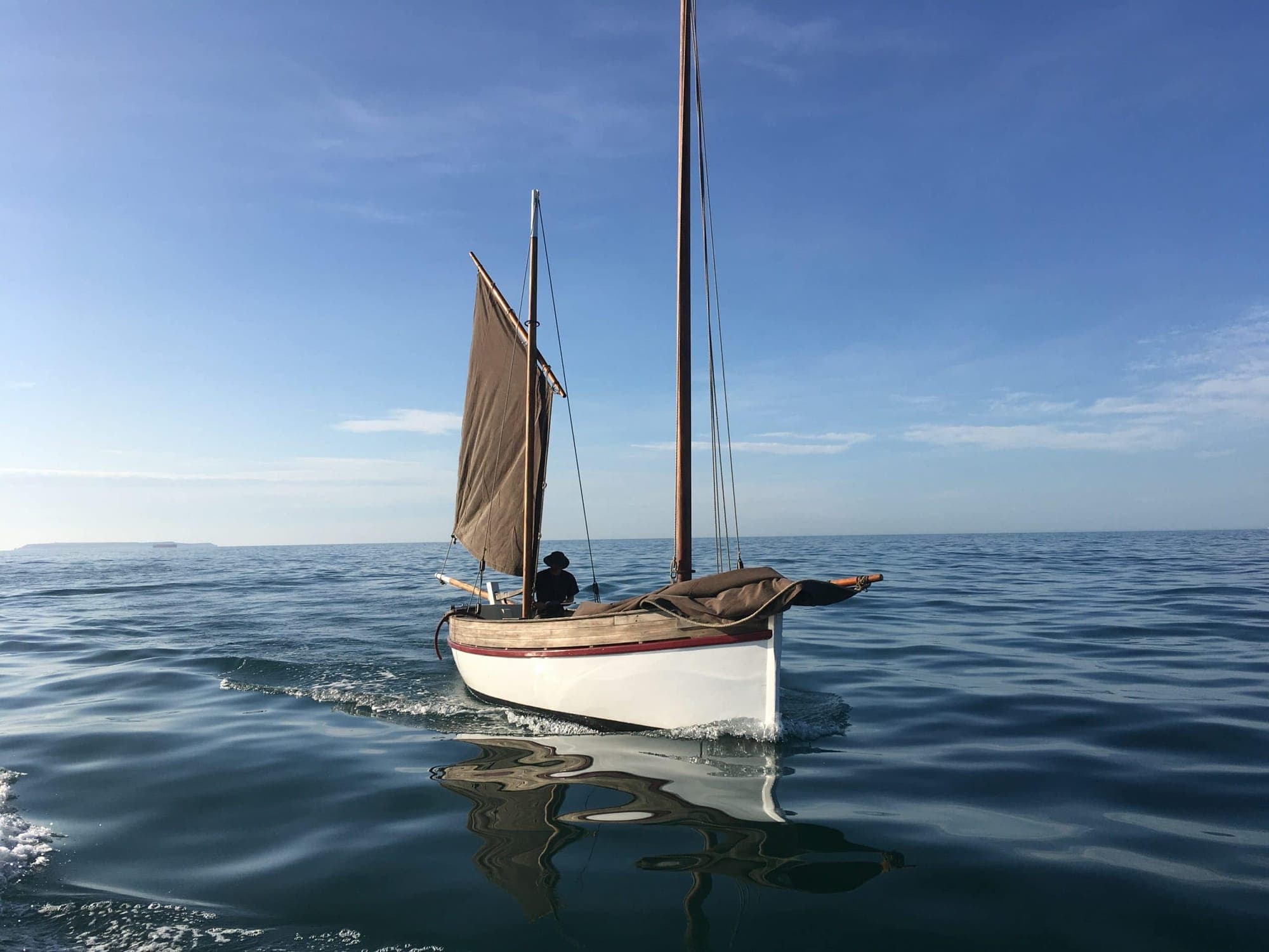 Traditional sailing boat under way on calm coastal water