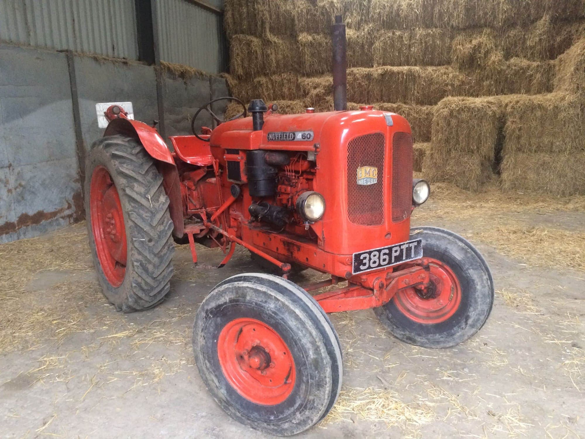 Vintage red Nuffield tractor inside a farm building