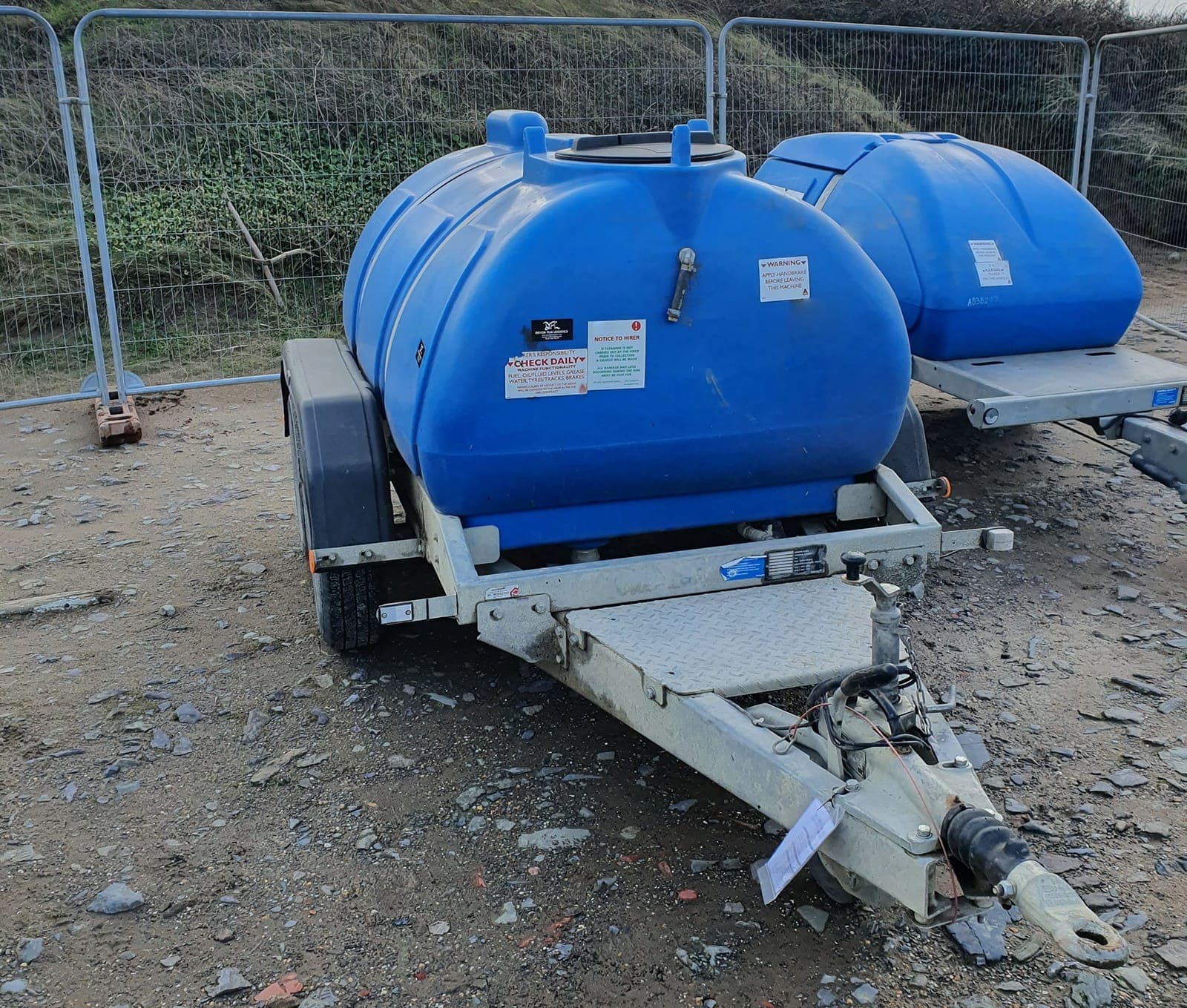 Two blue towable water bowsers at a temporary site